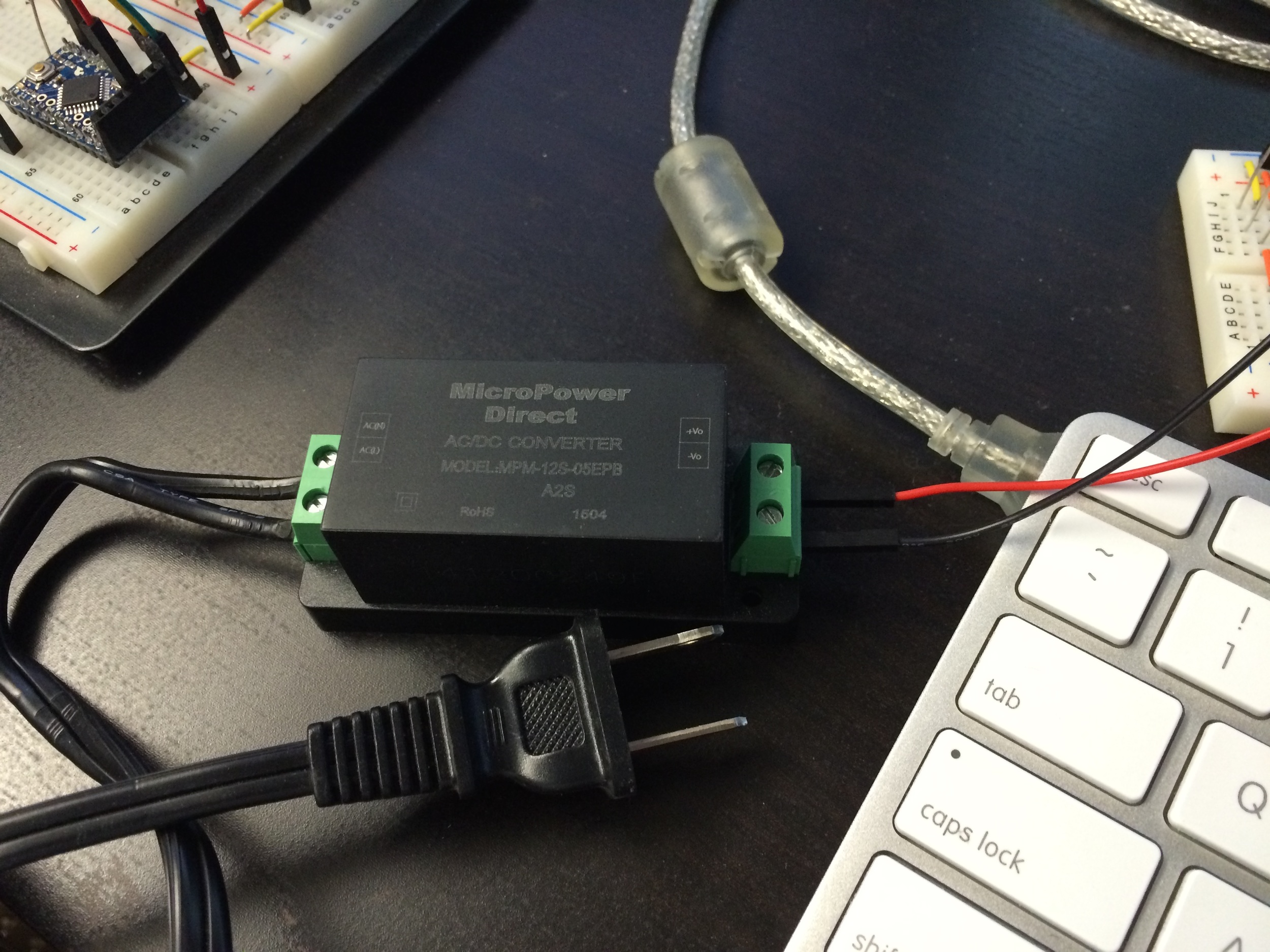 The MPM-12S-05EPB AC-DC switching power supply with AC cord and jumper wires attached securely
